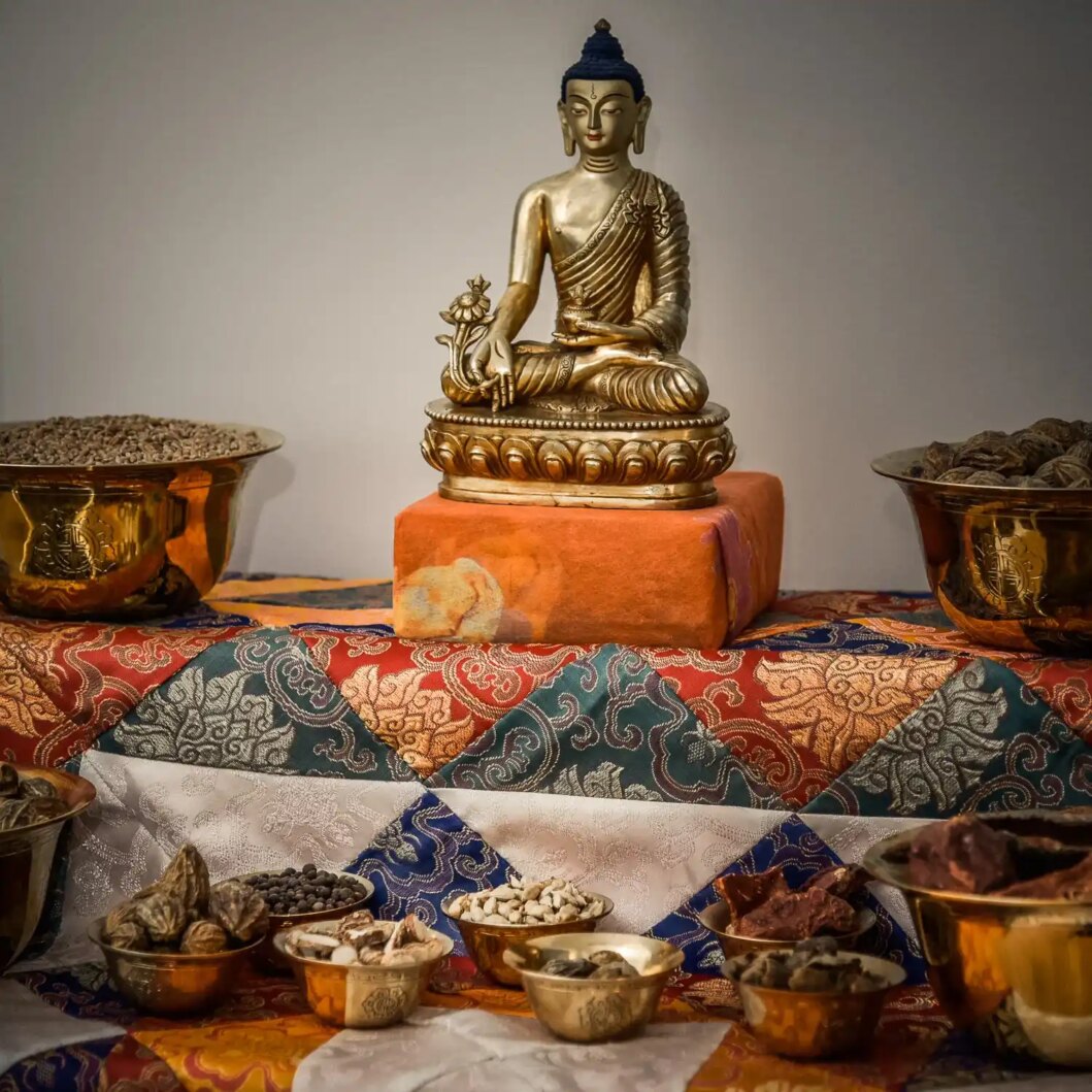 De Meidicijn boeddha met in de linkerhand myrobalanen. Op de voorgrond staan bakjes met Tibetaanse Kruiden die gebruikt voor voor Padma.